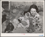 Mrs. Holley holding her baby while playing Fforty-two at party after literary society meeting. Pie Town, New Mexico. Mrs. Holley and her husband farmed in Texas before homesteading in Pie Town, New Mexico