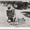 Faro Caudill building a fire to cook dinner while he moves his dugout. Pie Town, New Mexico
