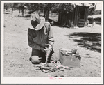 Faro Caudill building a fire to cook dinner while he moves his dugout. Pie Town, New Mexico