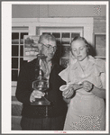 Mr. Besson, president of the literary society holds the lamp for Mrs. Caudill, secretary, during a song at the literary society. Pie Town, New Mexico