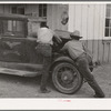 Garage owner and farmer working on a car. Pie Town, New Mexico. The young man who owns the filling station, blacksmith shop, and garage came out from Texas when he could not get work either on the farms or in the farming community towns there