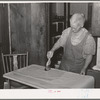Mrs. George Hutton brushing on paste on wall paper which her son is hanging for her. Pie Town, New Mexico