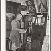 Mrs. George Hutton, homesteader, in front of her bookcase. Pie Town, New Mexico