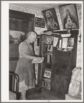 Mrs. George Hutton, homesteader, in front of her bookcase. Pie Town, New Mexico