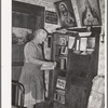 Mrs. George Hutton, homesteader, in front of her bookcase. Pie Town, New Mexico