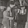 Mrs. George Hutton, homesteader, in front of her bookcase. Pie Town, New Mexico