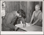 Mrs. George Hutton and her son measure off paper for the kitchen. Pie Town, New Mexico