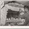 Jack Whinery does some repair work on the window in his dugout. The window was made from the windshield of the worn-out car which brought this family to Pie Town, New Mexico, from West Texas