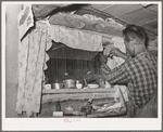 Jack Whinery does some repair work on the window in his dugout. The window was made from the windshield of the worn-out car which brought this family to Pie Town, New Mexico, from West Texas