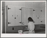 Wife of member of the Casa Grande Farms working at her kitchen sink. Pinal County, Arizona
