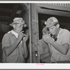 Workers on the hay-gathering and chopping machine taking time out for a cigarette. The goggles and masks are essential because of the severe dust. Casa Grande Valley Farms, Pinal County, Arizona