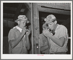 Workers on the hay-gathering and chopping machine taking time out for a cigarette. The goggles and masks are essential because of the severe dust. Casa Grande Valley Farms, Pinal County, Arizona