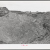 Sacramento Pit copper mine at Bisbee, Arizona. This is a pit 435 feet deep. In 1911 a shaft was sunk into the slopes of the east wall. In 1917 a dynamite charge blew off the top rock of the crown and dredges were worked to excavate the pit's ore bodies