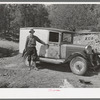 Eugene Davis standing by the side of his adapted truck which carries him about the country on his search for gold. Pinos Altos, New Mexico