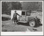 Eugene Davis standing by the side of his adapted truck which carries him about the country on his search for gold. Pinos Altos, New Mexico