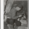 Eugene Davis, gold prospector, looking into chest where he has stored his belongings. Pinos Altos, New Mexico