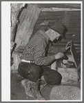 Eugene Davis, gold prospector, looking into chest where he has stored his belongings. Pinos Altos, New Mexico