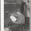 Eugene Davis, gold prospector, reading over location notice form which must be filed along with mining claim. Pinos Altos, New Mexico