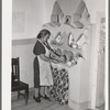 Wife of Spanish-American family arranging things in adobe cupboard which she designed and built. Chamisal, New Mexico