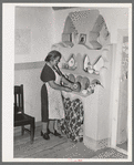 Wife of Spanish-American family arranging things in adobe cupboard which she designed and built. Chamisal, New Mexico