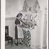 Wife of Spanish-American family arranging things in adobe cupboard which she designed and built. Chamisal, New Mexico