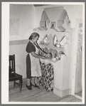 Wife of Spanish-American family arranging things in adobe cupboard which she designed and built. Chamisal, New Mexico