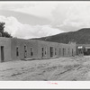 Row of adobe dwellings in Costilla, New Mexico. Well in square supplies several families with water