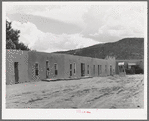 Row of adobe dwellings in Costilla, New Mexico. Well in square supplies several families with water