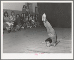 Spanish-American acrobat of traveling show. Audience in background. Penasco, New Mexico