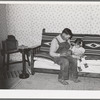 Spanish-American farmer and his daughter seated on couch which his son made at school workshop in Albuquerque. Chamisal, New Mexico