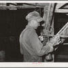 Workman weighing sample of gold ore and cyanide solution to determine if proper concentration of liquid is being maintained. Mogollon, New Mexico
