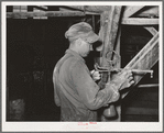 Workman weighing sample of gold ore and cyanide solution to determine if proper concentration of liquid is being maintained. Mogollon, New Mexico