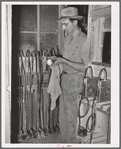 Workman checking miners' lights. Batteries of these lights are checked every day. Mogollon, New Mexico