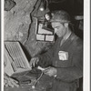 Miner inserting fuse into stick of dynamite. Mogollon, New Mexico