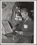 Miner inserting fuse into stick of dynamite. Mogollon, New Mexico