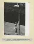 A Po[l]ish girl in a national costume hoists the flag in the Polish Camp for girls in Gronebic, unoccupied France, 1941.