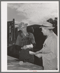 Freight train conductor talking to railroad man who was in charge of shipping livestock. Cimarron, Colorado