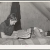 Concrete worker resting while his wife looks for apartments in the want ads. He works the night shift. They have been unable to find a reasonably priced apartment and are living in a tent. They are from Washington. Pacific Beach, California