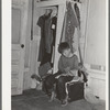Small boy, son of carpenter from Hobbs, New Mexico, reading funny papers in corner of room in tourist court. Lack of adequate closet space is evident. Corpus Christi, Texas