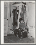 Small boy, son of carpenter from Hobbs, New Mexico, reading funny papers in corner of room in tourist court. Lack of adequate closet space is evident. Corpus Christi, Texas
