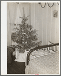 Baby and Christmas tree in corner of living room in home of construction workman. This family came to Corpus Christi from northwest Texas eight months ago