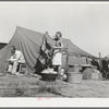 Roofer and his daughter in front of tent home. Corpus Christi, Texas. This man has been working at the naval air training base but hurt his back a week ago and is now unable to work