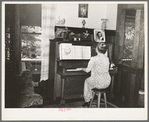 Fruit farmer's wife playing piano. Placer County, California. Because they have not changed the variety of plums and pears which they raise to meet changed market conditions they have gone further and further into debt to the Federal Land Bank