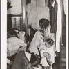 Corner of bedroom with Negro housewife examining bed clothing chewed by rats. Chicago, Illinois
