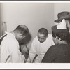 Doctors examining baby whose parents have just brought him into the clinic at the Negro hospital. Chicago, Illinois
