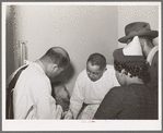 Doctors examining baby whose parents have just brought him into the clinic at the Negro hospital. Chicago, Illinois