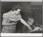 Teacher helps pupil with his reading, FSA (Farm Security Administration) camp for farm workers. Caldwell, Idaho. School is held at the camp because of lack of room in city schools