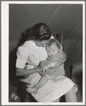 Nurse looks at cut on baby's arm at the FSA (Farm Security Administration) migratory labor camp mobile unit. Wilder, Idaho. The nurse not only is in attendance at the trailer clinic, but makes her regular rounds of calls to the tents