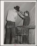 Farm workers fixing up the tent in which they will live at the FSA (Farm Security Administration) migratory labor camp mobile unit. Wilder, Idaho