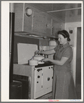 Wife of aircraft worker at the stove in her trailer home at the FSA (Farm Security Administration) camp for defense workers. San Diego, California